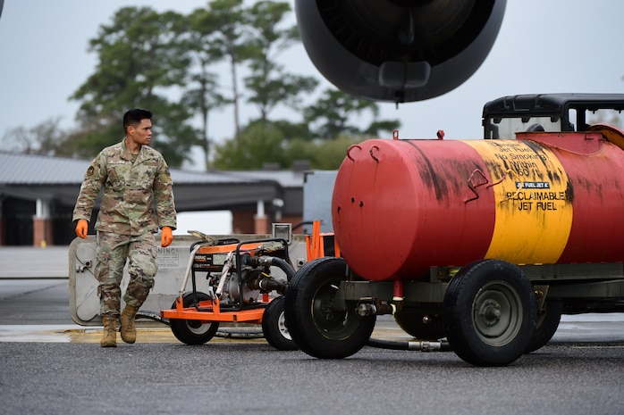 A photo of an Airman walking around a fuel tank.