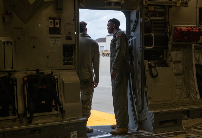 A photo of two Airmen talking inside an aircraft.