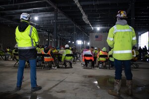 Construction workers stand in interior construction site
