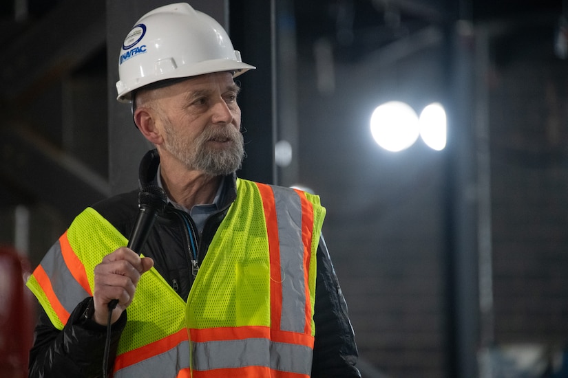 Lead construction worker holding microphone about to speak.