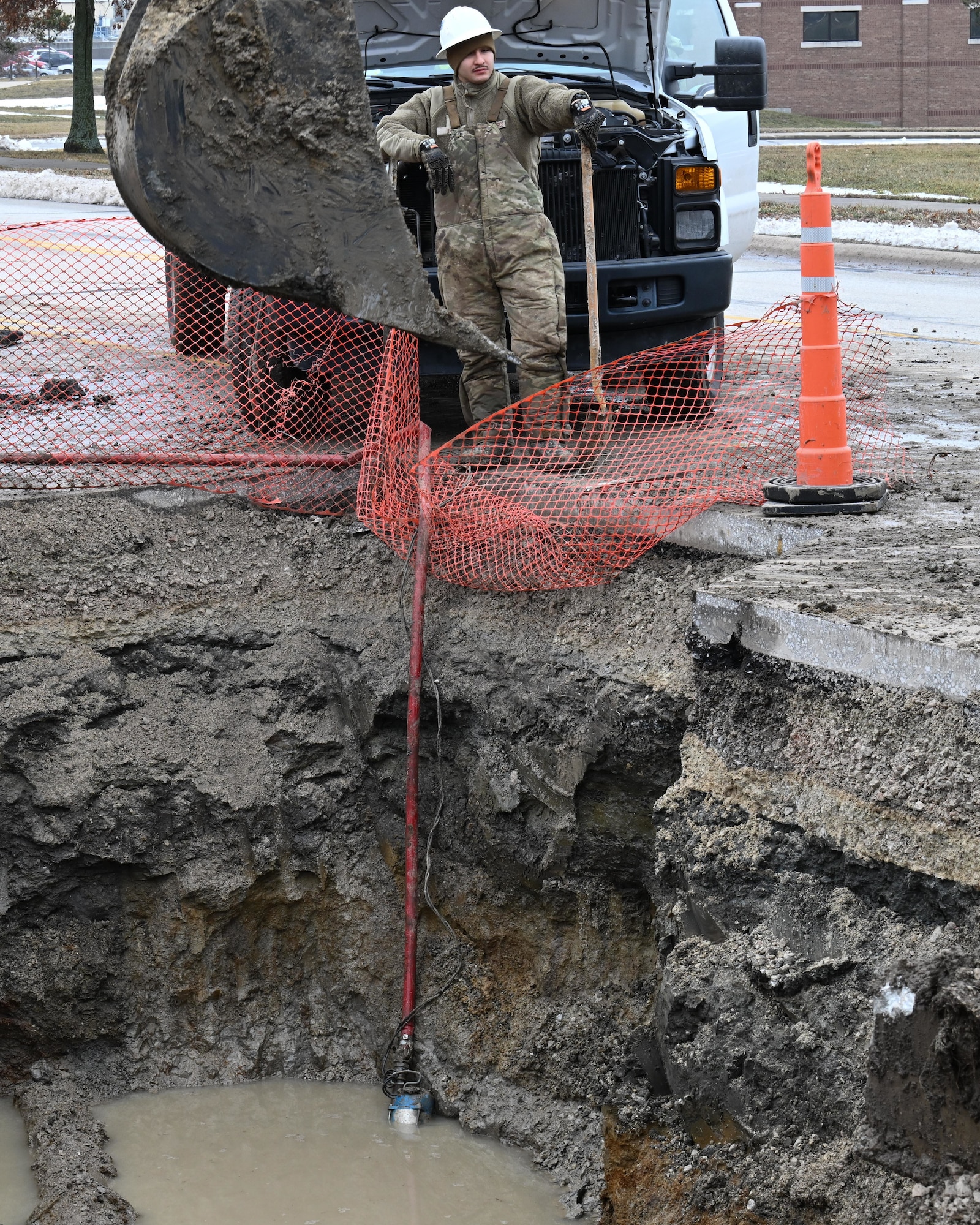 U.S. Airman 1st Class Paul Ortiz, 509th Civil Engineer Squadron water and fuels systems maintenance journeyman, waits as the site is drained of water so he can operate on a broken water main at Whiteman Air Force Base, Mo., Jan 25, 2024. Repairs of the watermain and construction was delayed due to freezing rain and ice. (U.S. Air Force photo by Airman 1st Class Matthew S. Domingos)