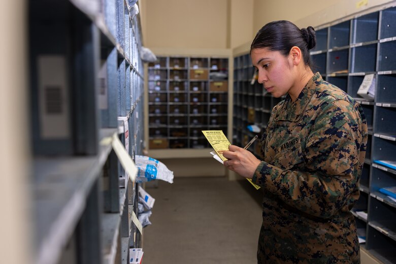 U.S. Marine Corps Lance Cpl. Ericka ValenciaReyes, a postal clerk with Headquarters and Support Battalion, Marine Corps Installations Pacific-Marine Corps Base Camp Butler, reviews the mail in the boxes at the Camp Foster Post Office, on Okinawa, Japan, Jan. 10, 2024.  At 9-years-old, ValenciaReyes left her hometown in N.C. for Mexico with her mother after her parents’ divorce. She decided to move back to the states and join the Marine Corps when she turned 18. Despite fracturing her pelvic bone in boot camp, she persevered and went on to graduate from Papa Company in Feb. 2021. She moved to Okinawa in July, 2022. (U.S. Marine Corps photo by Cpl. Martha Linares)