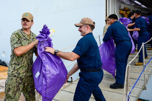 U.S. Navy Sailors participate in a working party to onload mail onto the hospital ship USNS Mercy (T-AH 19) during Pacific Partnership 2024-1 while anchored off Honiara, Solomon Islands, Dec. 1, 2023. Pacific Partnership, now in its 19th iteration, is the largest multinational humanitarian assistance and disaster relief preparedness mission conducted in the Indo-Pacific and works to enhance regional interoperability and disaster response capabilities, increase security stability in the region, and foster new and enduring friendships. (U.S. Navy photo by Mass Communication Specialist 2nd Class Celia Martin)