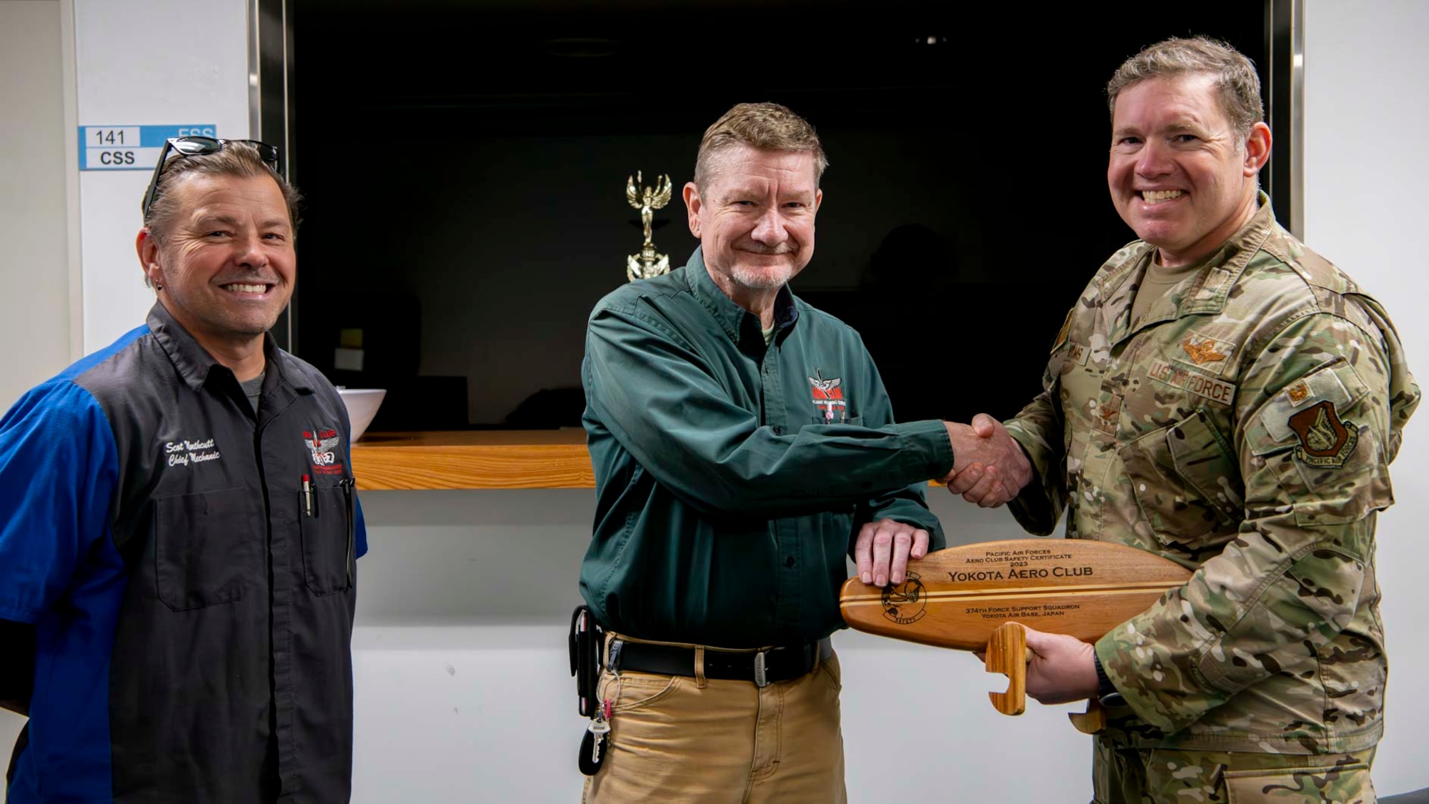 Two men receive an award from a military member.