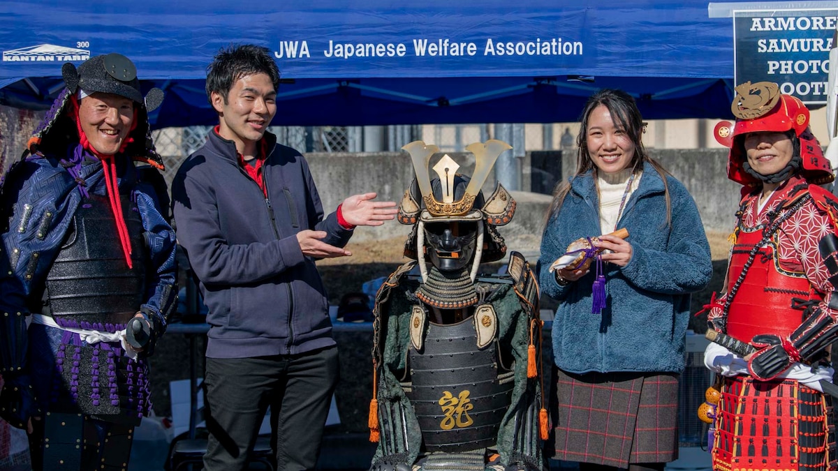 A pair of armored samurai pose for a photo with people.