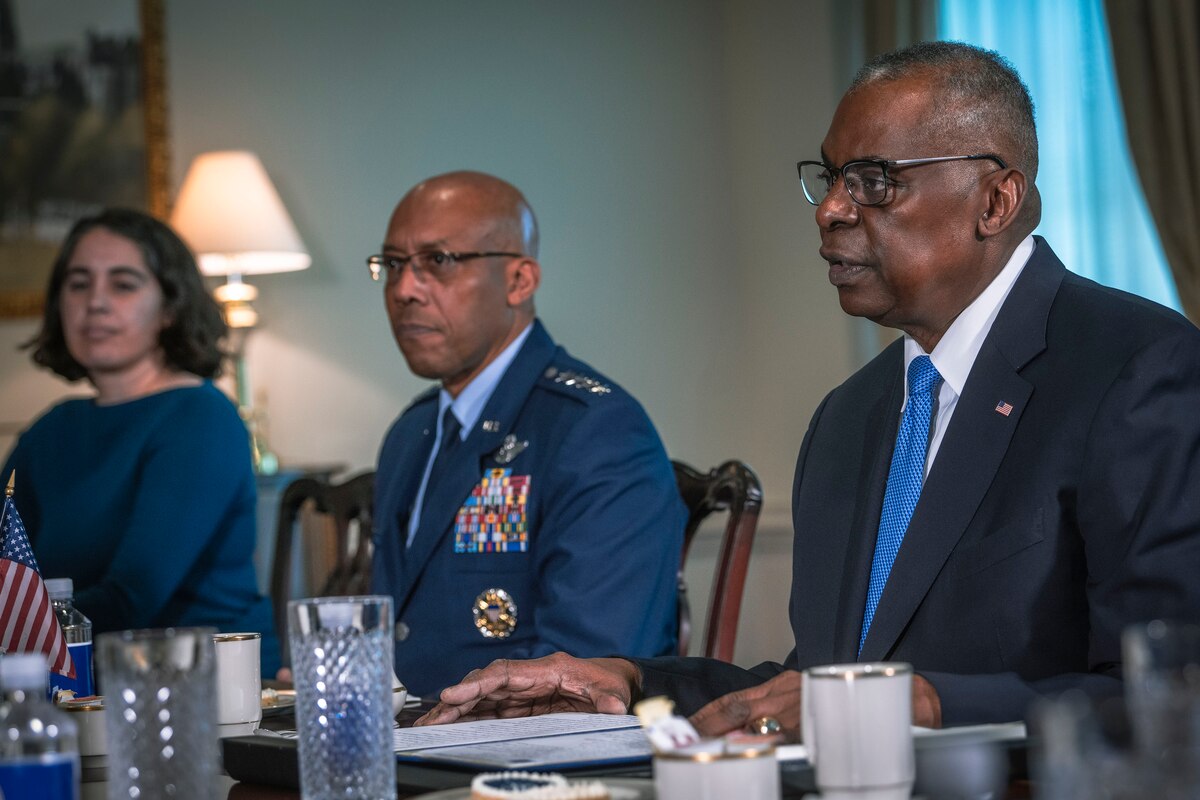 Three people sit at a conference table.