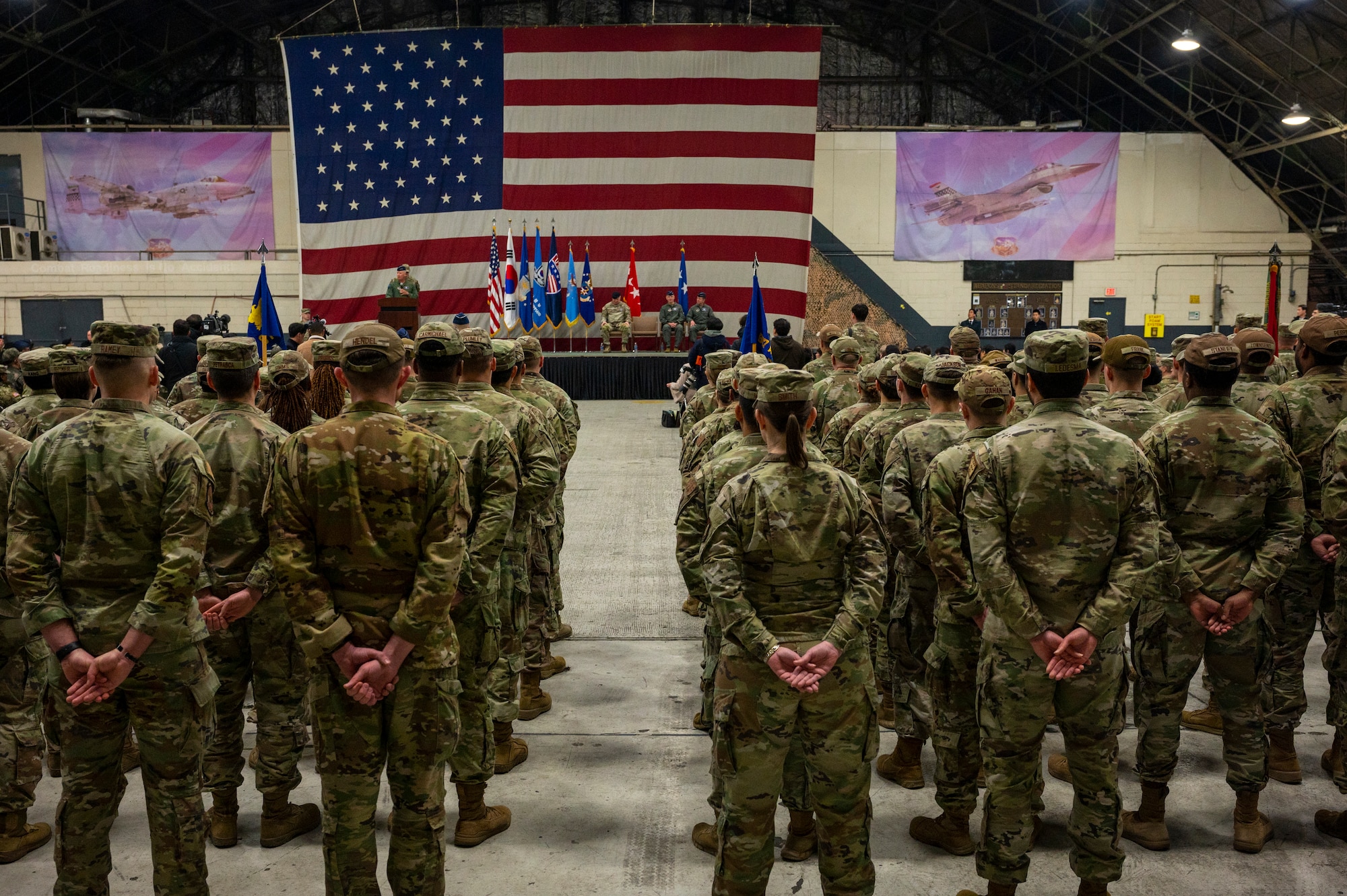 Two formations of U.S. Air Force Airmen and U.S. Army Soldiers appear from the back, looking toward a stage with a large US flag backdrop during the Seventh Air Force change of command ceremony, at Osan Air Base.