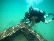 240109-N-PI330-2047 SAO TOME, São Tomé and Principe (Jan. 9, 2024) Construction Mechanic 2nd Class Zach Reisinger, assigned to Underwater Construction Team 1 (UCT 1), attaches lift bags to a submerged container during an underwater survey of a coast guard pier in São Tomé, São Tomé and Principe,  Jan. 9, 2024. UCT 1 is on a scheduled deployment in the U.S. Naval Forces Europe area of operations, employed by the U.S. 6th Fleet to defend U.S., allied and partner interests. (U.S. Navy photo by Mass Communication Specialist 2nd Class Andrew Waters)