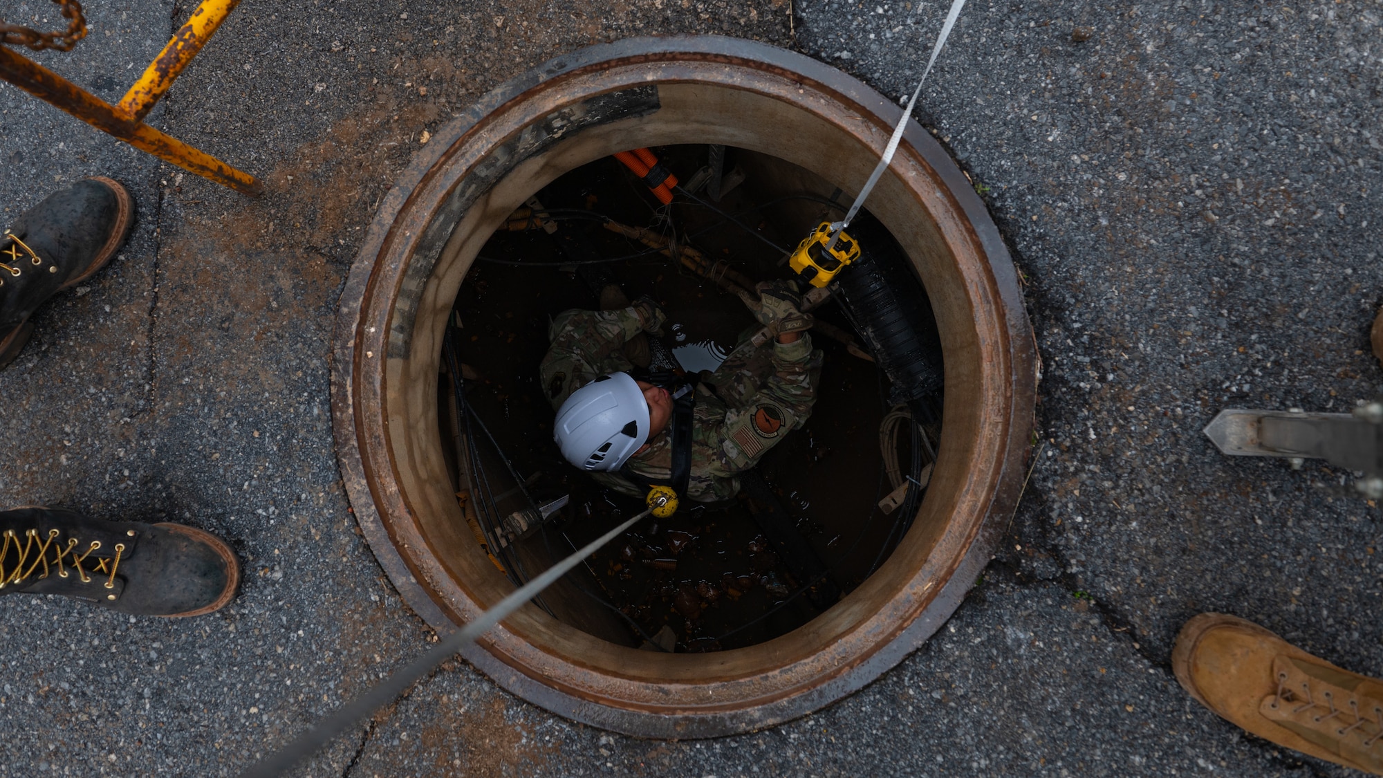 An Airman inside of a manhole.