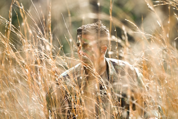 Lt. Jacob Westerberg, research psychologist for the Robert E. Mitchell Center (REMC) RPOW studies, crouches in a field wearing camouflage and face-paint to re-enact scenes from his training while describing his professional take on the psychological experiences faced by those having to endure real-life survival scenarios like those taught in the survive evade resist and escape (SERE) training. Photos were captured onboard Naval Air Station Pensacola, Jan. 11. The Robert E. Mitchell Center houses the POW research studies program for all branches the armed forces and has been an active program for 50 years as of 2023. (U.S. Navy photo by Mass Communication Specialist 1st Class Russell Lindsey SW/AW)