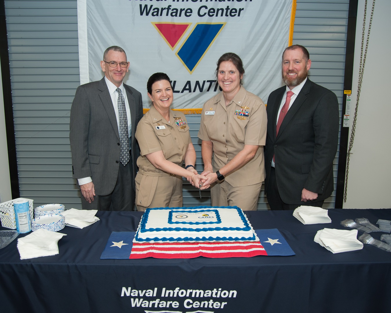 [Left to Right] Naval Information Warfare Center (NIWC) Atlantic Executive Director Peter Reddy, Tactical Networks Program Officer (PMW 160) PEO C4I Program Manager Capt. Catherine Boehme, NIWC Atlantic Commanding Officer Capt. Nicole Nigro, and NIWC Atlantic Navy Afloat Network and C2 Apps Division Head prepare to cut the cake at the ribbon cutting ceremony for the new Network Integration and Engineering Facility (NIEF) Lab of the Future on January 25 at Naval Station Norfolk.