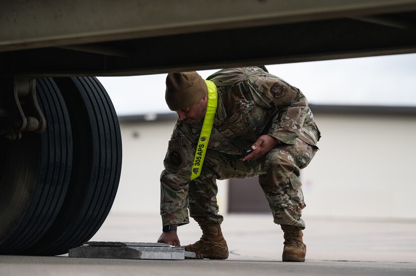 A U.S. Air Force Airman from the 305th Aerial Port Squadron removes truck parking blocks at Joint Base McGuire-Dix-Lakehurst, N.J., Jan. 27, 2024. More than 1,500 New Jersey Army National Guard Soldiers are deploying to support U.S. Central Command’s Combined Joint Task Force-Operation Inherent Resolve. This is the largest deployment of NJARNG Soldiers since 2008. (U.S. Air Force photo by Senior Airman Sergio Avalos)