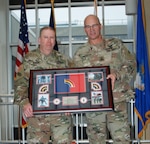 New York Army National Guard Chief Warrant Officer 4 Albert Thiem, left, who also served as a sergeant and a lieutenant colonel, receives a retirement gift from Maj. Gen. Thomas Spenser during a ceremony at New York National Guard headquarters in Latham, N.Y., Jan. 26, 2024.