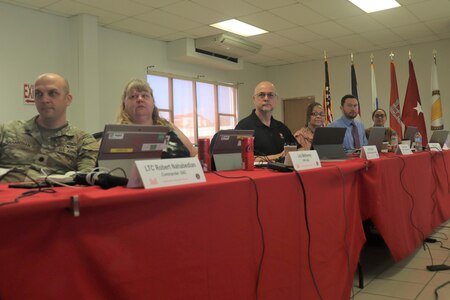 Lt. Col. Nahabedian seated with civilians at table covered win red tablecloth.