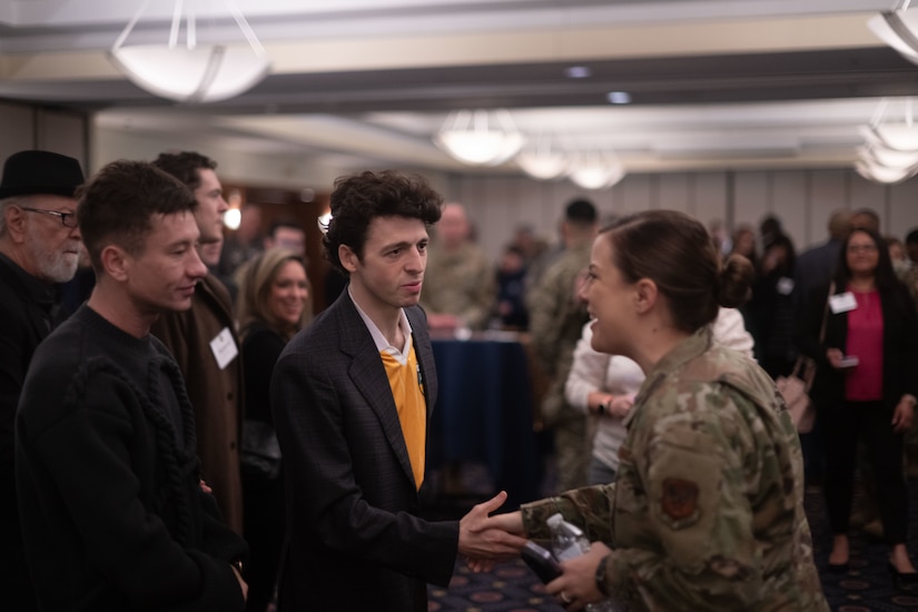 A group of people and two of them shake hands.