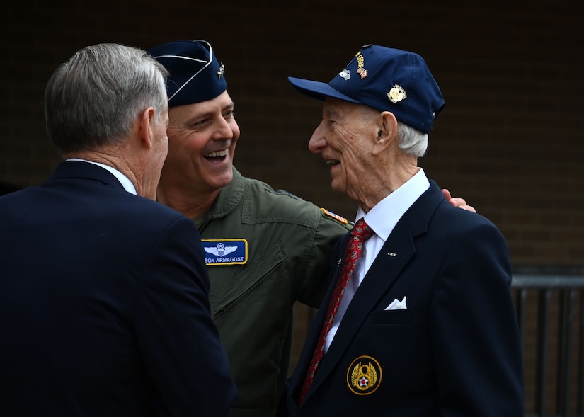 Three men speak together outside.