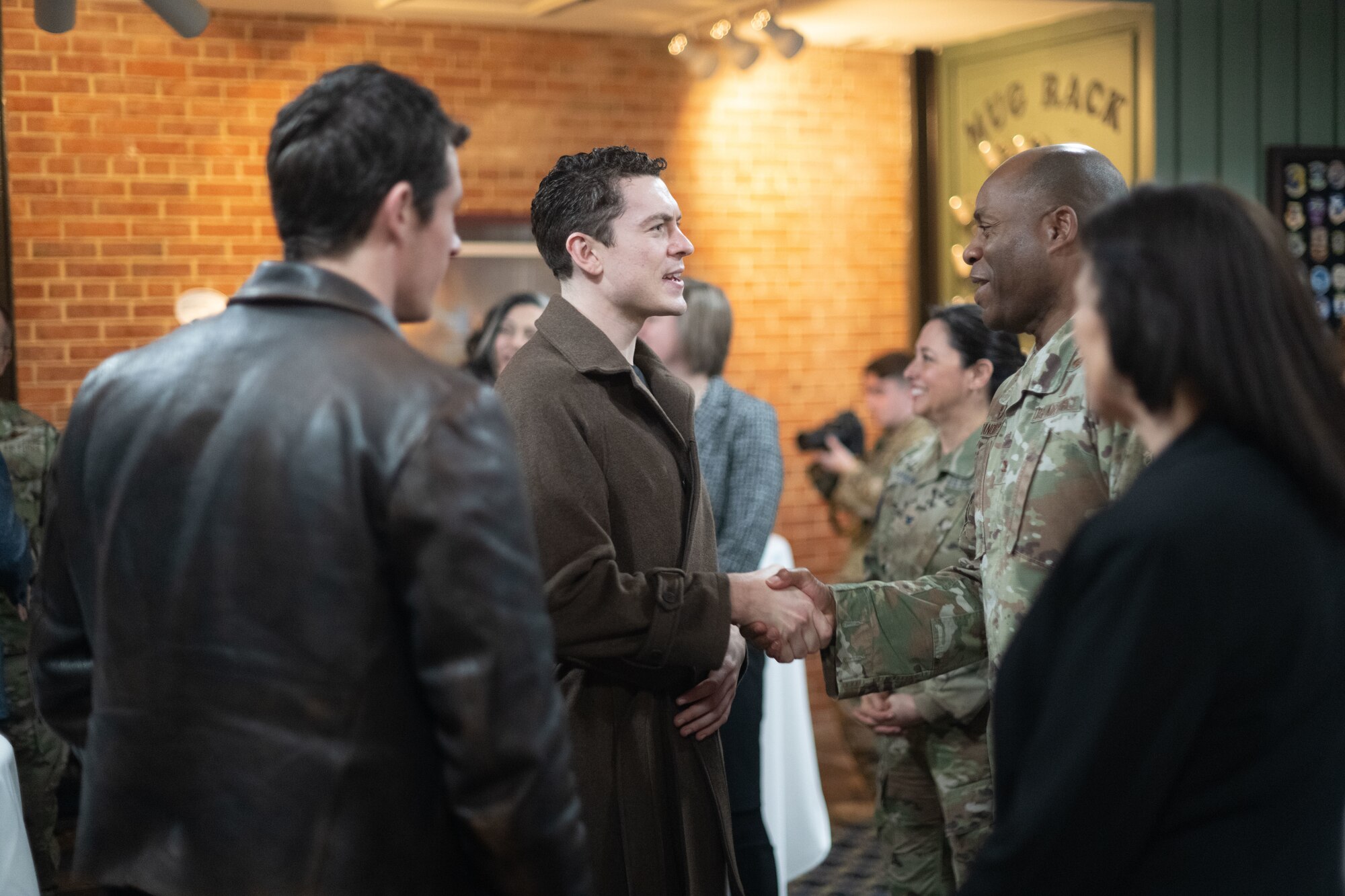 Two people shaking hands in a group of people.