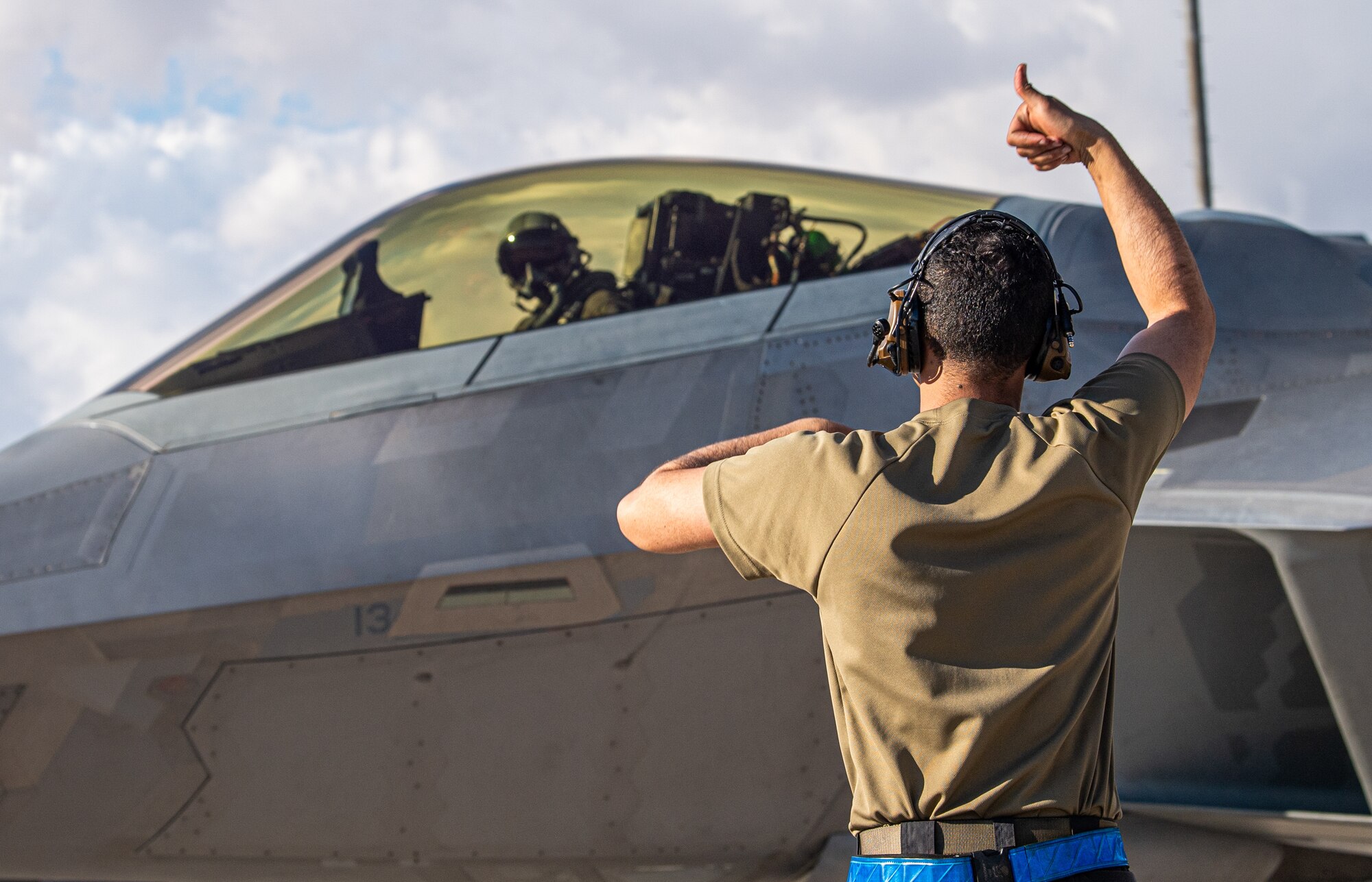 U.S. Air Force Staff Sgt. Aubrey Crenshaw, a crew chief with the 525th Expeditionary Fighter Generation Squadron, Joint Base Elmendorf-Richardson, Alaska, marshals an F-22 Raptor piloted by U.S. Air Force 1st Lt. Jake Heydinger, 525th Expeditionary Fighter Squadron, in support of Exercise Bamboo Eagle 24-1 at Nellis Air Force Base, Nevada, Jan. 25, 2024.
