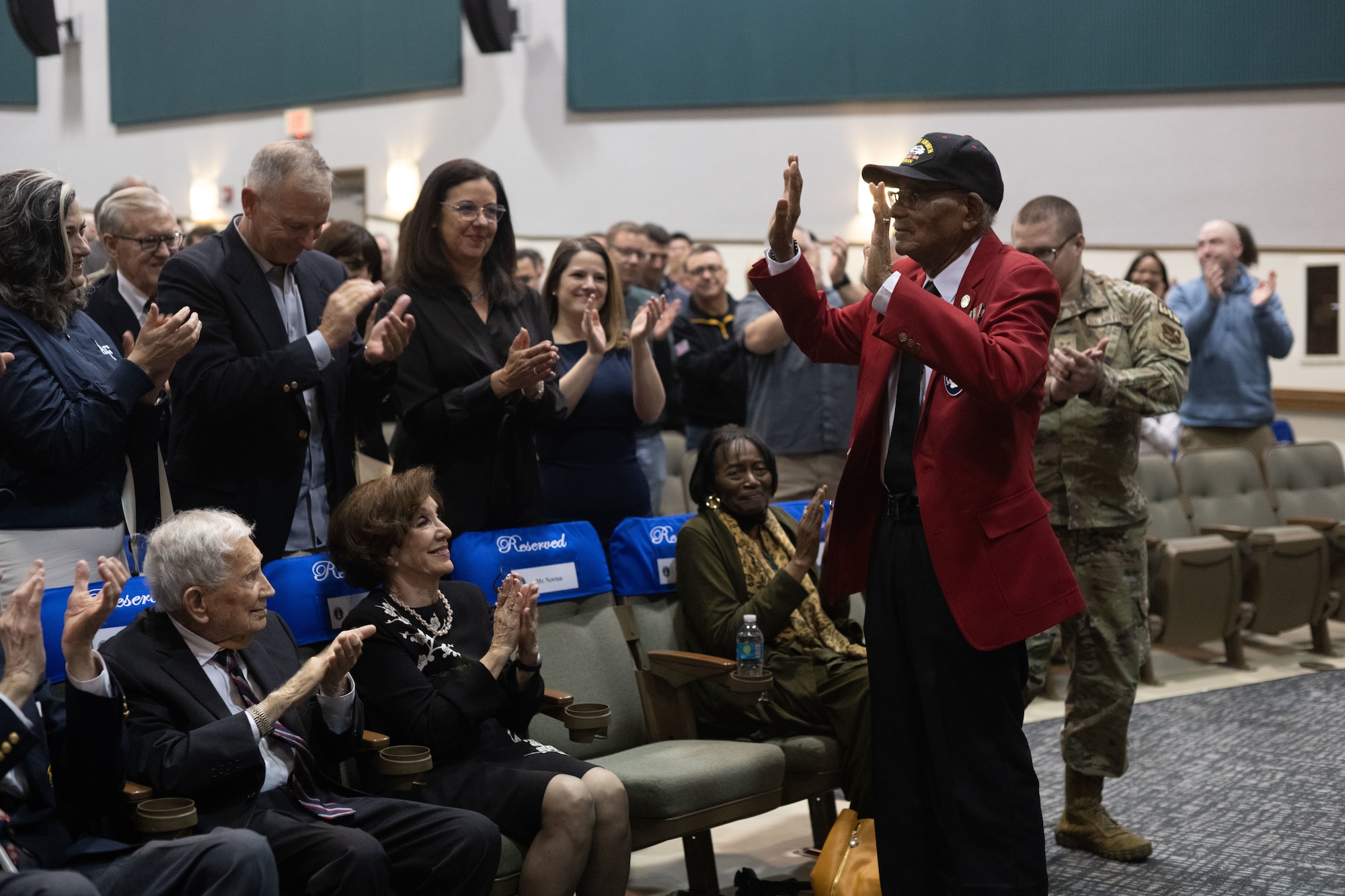 A man waves as an audience applauds.