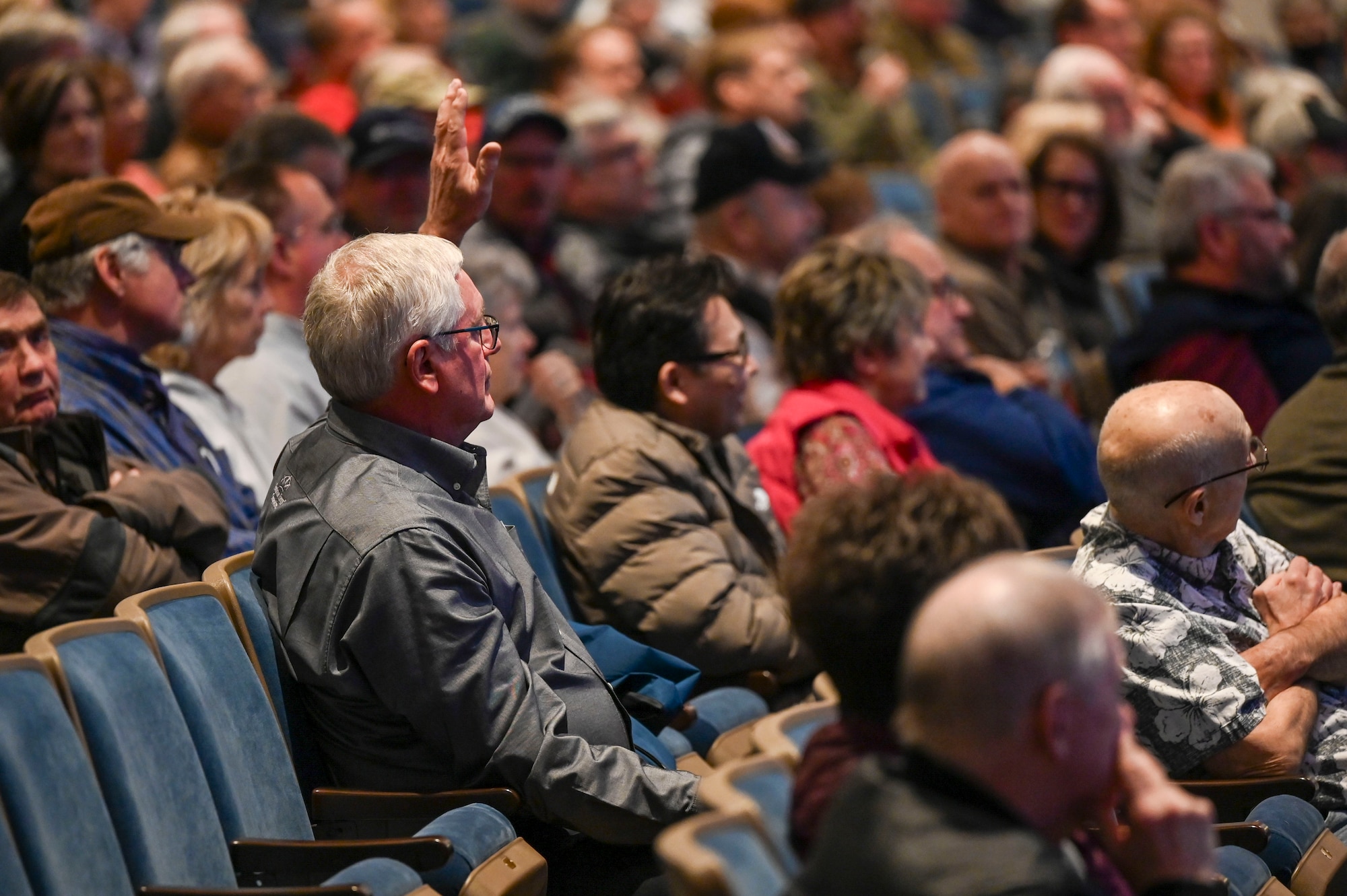 A man raises his hand in the middle of an audience