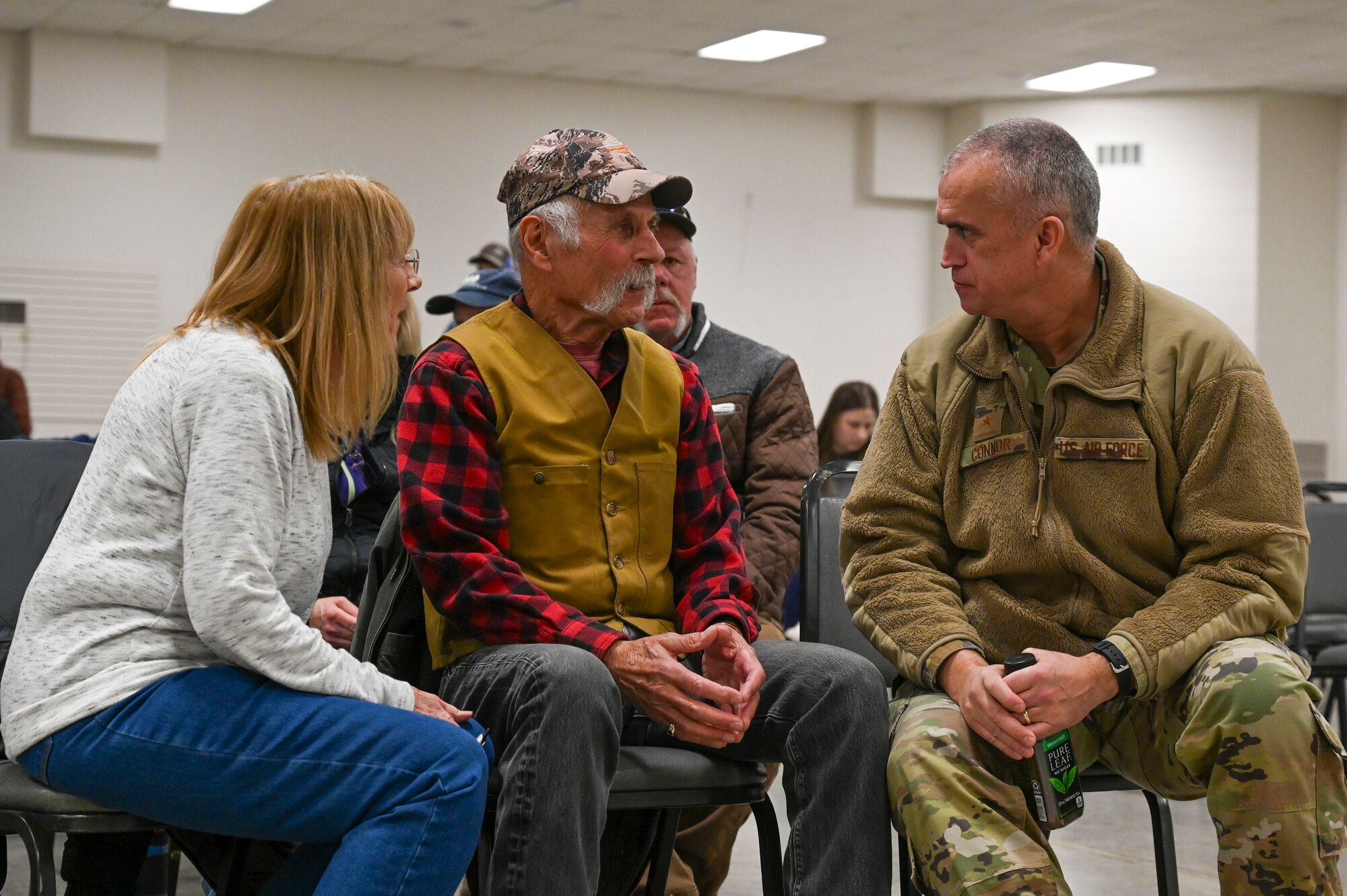 A man speaks to a man and woman while sitting down in chairs