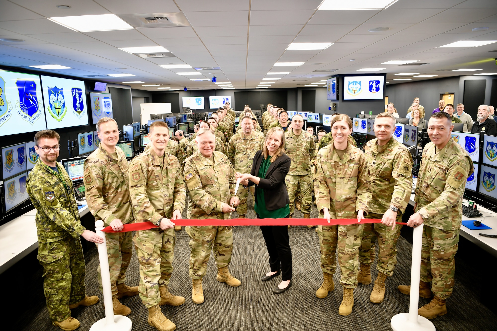 A red ribbon is cut with large scissors to open the new Western Air Defense Sector's Agile Operations Center