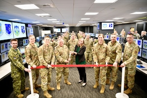 A red ribbon is cut with large scissors to open the new Western Air Defense Sector's Agile Operations Center