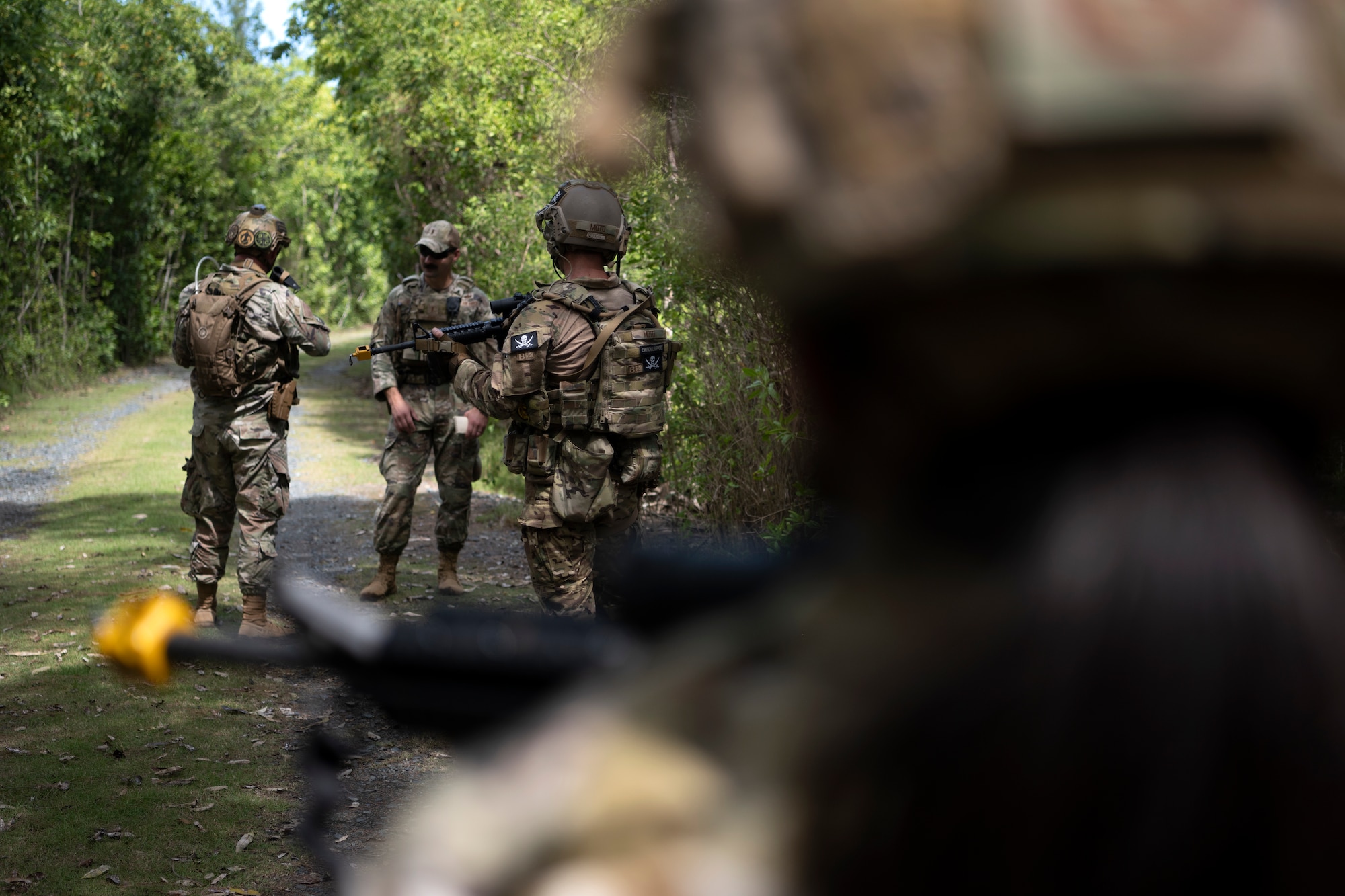 U.S. Airmen with the 156th Security Operations Squadron, Puerto Rico Air National Guard, and the 123rd Contingency Response Group, Kentucky Air National Guard, convene on a trail during air base ground defense training at Muñiz Air National Guard Base in Carolina, Puerto Rico, Sept. 21, 2023. During the training, Airmen reinforced air base ground defense skills utilized during contingency response operations in contested environments by practicing radio communications, warning and operation orders, vehicle searches, vehicle take-downs, close-quarter battle, and small team tactics. (U.S. Air National Guard photo by Master Sgt. Rafael D. Rosa)