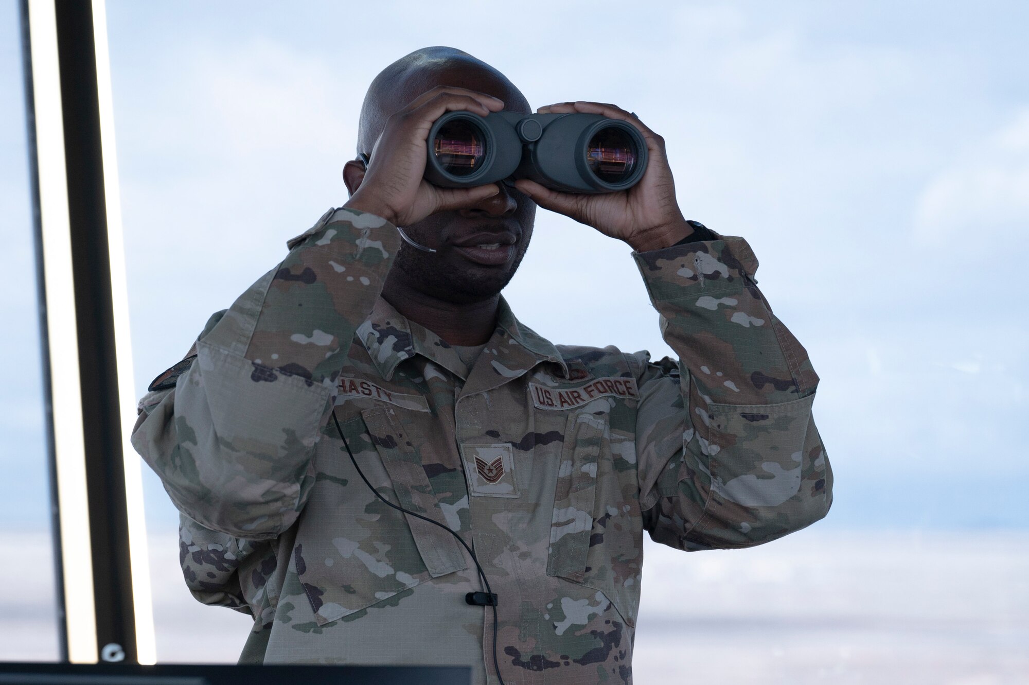 U.S. Air Force Tech. Sgt. Zackery Hasty, 54th  Operations Support Squadron senior watch supervisor, looks through his binoculars to locate aircraft on the flightline at Holloman Air Force Base, New Mexico, Jan. 24, 2024. Air traffic controllers operate air traffic systems to expedite the flow of all inbound and outbound aircraft on base. (U.S. Air Force photo by Airman 1st Class Michelle Ferrari)