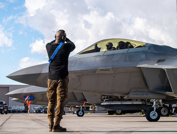 U.S. Air Force Airman First Class Kawan Thornton, a crew chief with the 525th Expeditionary Fighter Generation Squadron, Joint Base Elmendorf-Richardson, Alaska, marshals an F-22 Raptor piloted by U.S. Air Force 1st Lt. Jake Heydinger, 525th Expeditionary Fighter Squadron, in support of Exercise Bamboo Eagle 24-1 at Nellis Air Force Base, Nevada, Jan. 25, 2024.