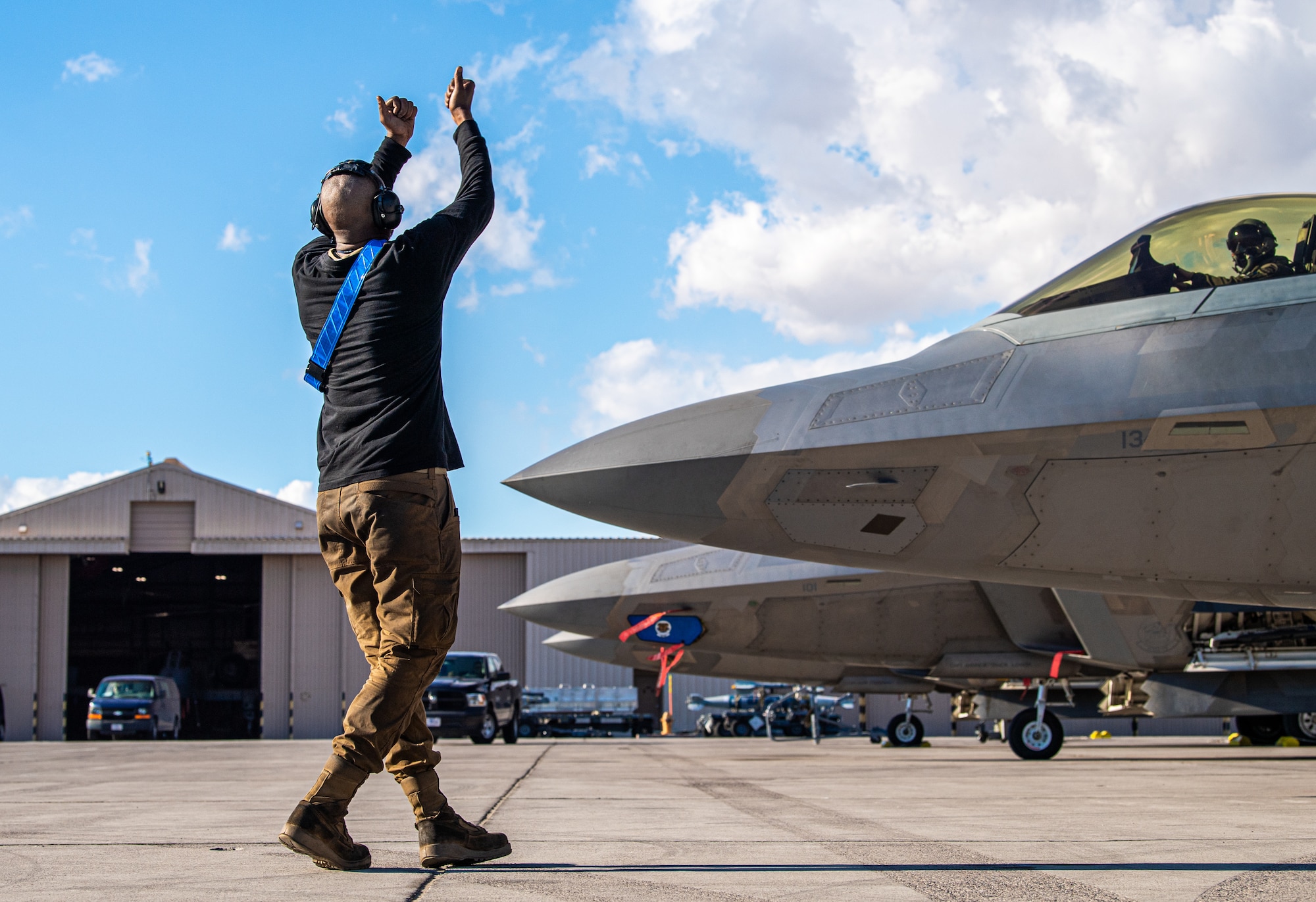 U.S. Air Force Airman First Class Kawan Thornton, a crew chief with the 525th Expeditionary Fighter Generation Squadron, Joint Base Elmendorf-Richardson, Alaska, marshals an F-22 Raptor piloted by U.S. Air Force 1st Lt. Jake Heydinger, 525th Expeditionary Fighter Squadron, in support of Exercise Bamboo Eagle 24-1 at Nellis Air Force Base, Nevada, Jan. 25, 2024.