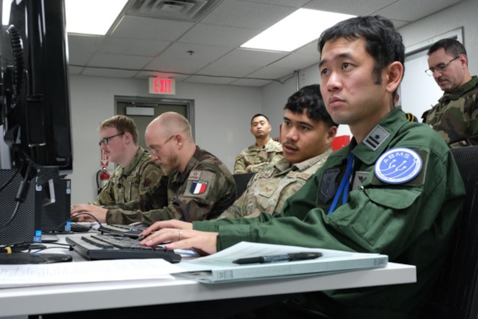 photo of US, Japan, and French military members working on computers