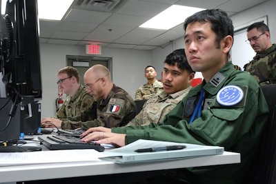 photo of US, Japan, and French military members working on computers