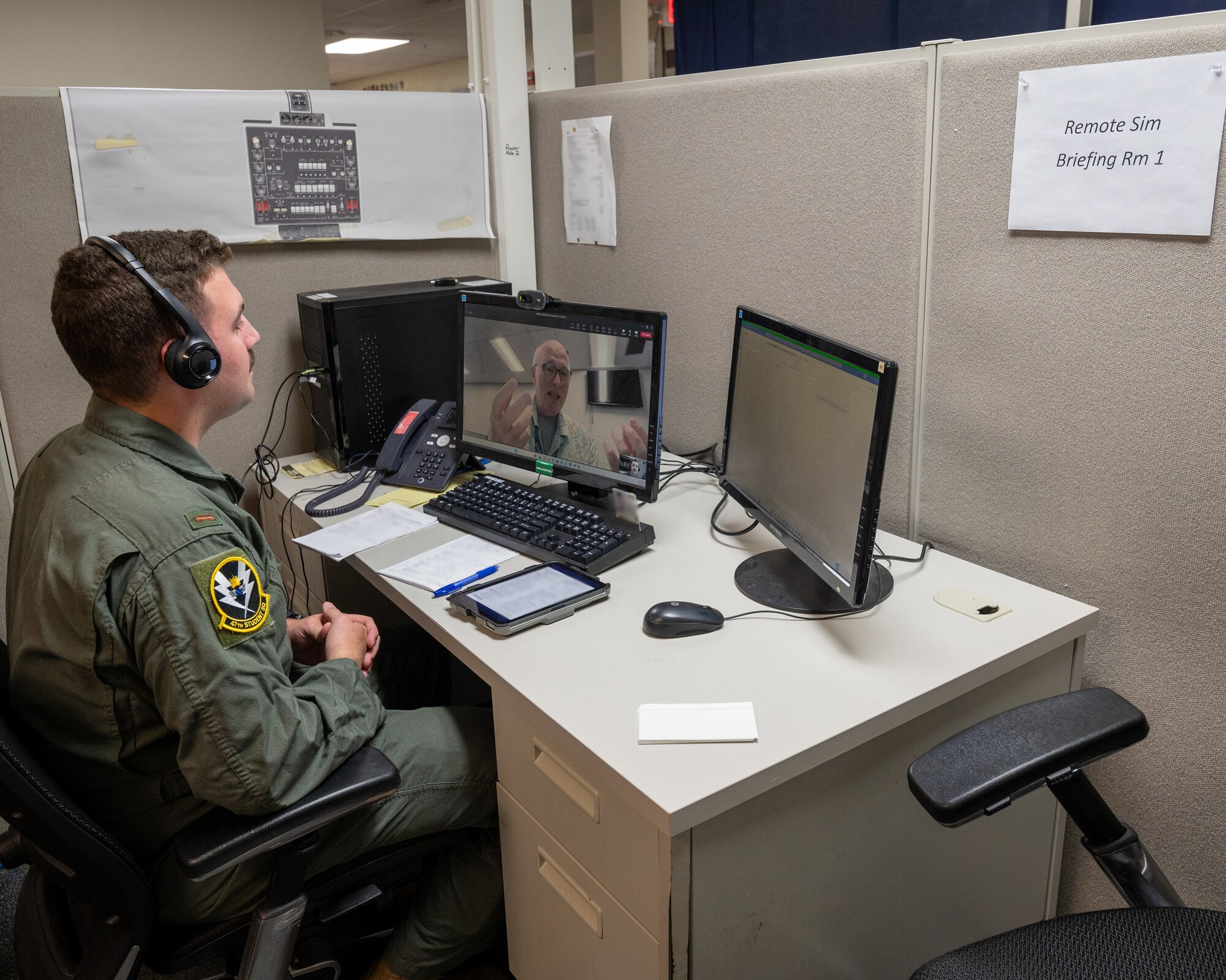 Flight instructor sits in front of screen.
