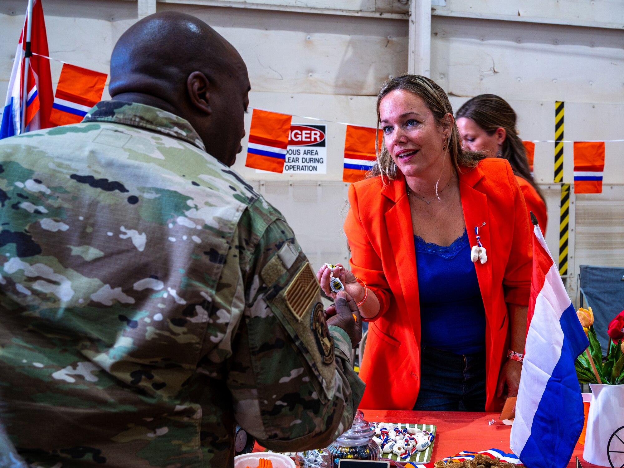 Esther Zwart, a military spouse with the Royal Netherlands Air Force F-35 Training Detachment attached to the 308th Fighter Squadron, hands an Airman a traditional dessert during the Luke Air Force Base International Festival 2024, Jan 26, 2024, at Luke AFB, Arizona.