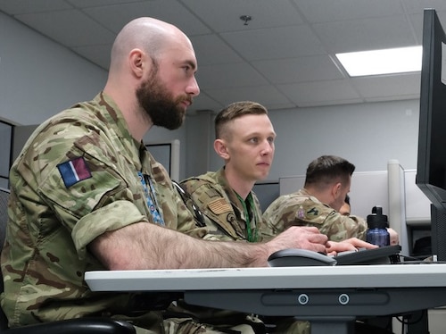 uniformed military members work on computers