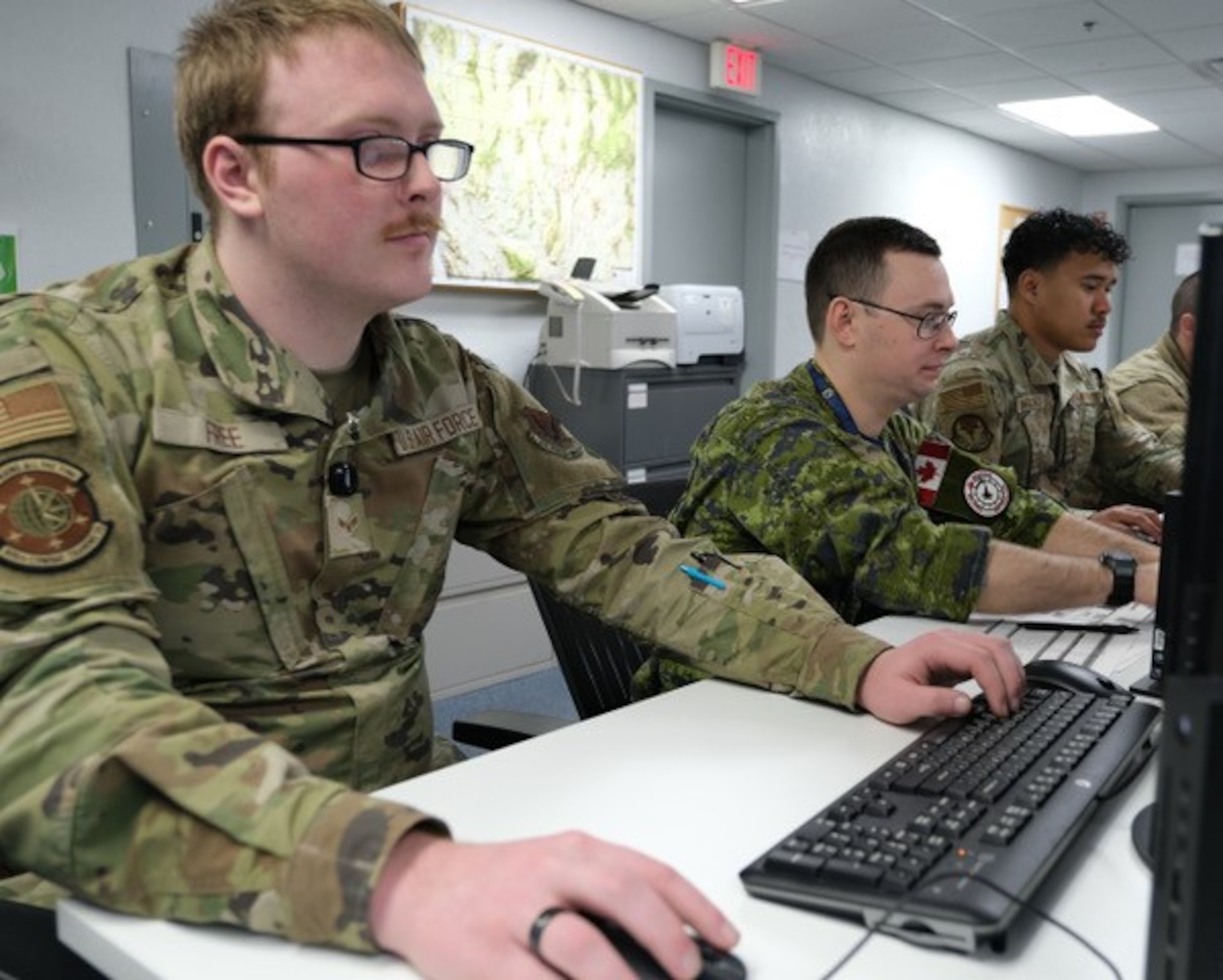 United States Airmen and a Royal Canadian Air Force member participate in the  Transformational Modeling for Battle Management experiment, using an artificial intelligence-enabled technology, known as “Match Effectors” at Nellis Air Force Base, Nevada, Dec. 4, 2023.   The 805th Combat Training Squadron, also known as the Shadow Operations Center – Nellis, executed their annual Capstone event by experimenting with and developing tactics, techniques, and procedures for integrated two-way kill-chain automation between the operational and tactical command and control including battle management levels, to create competitive advantages for the United States and its allies and partners.  (The image has been altered by removing badges for security purposes and cropped to focus on the subject.) (U.S. Air Force photo by Keith Keel)