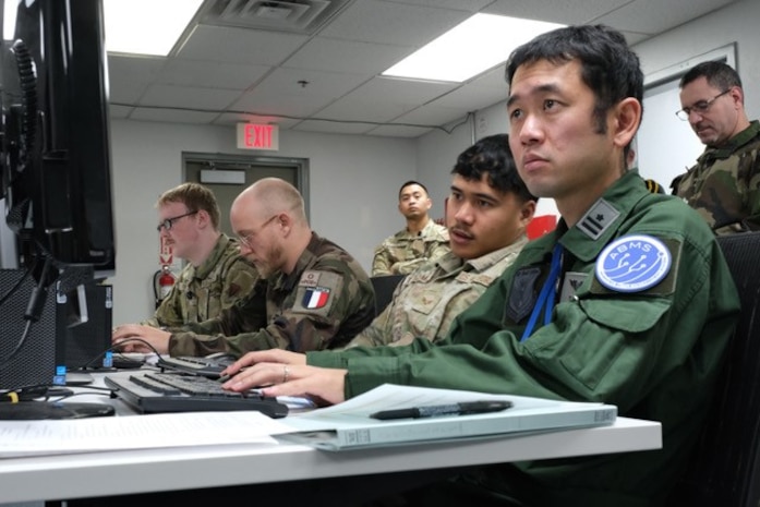 photo of US, Japan, and French military members working on computers