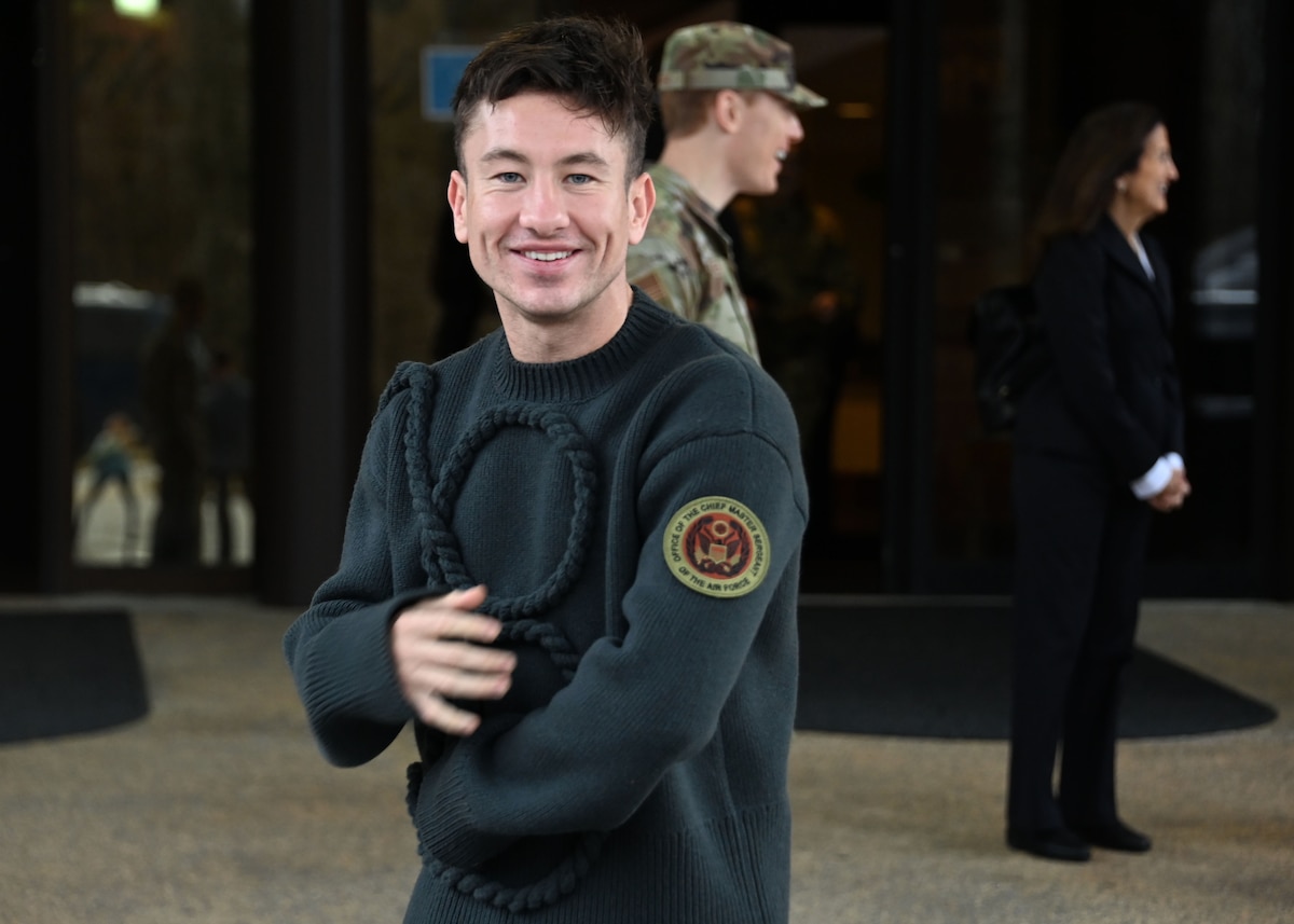 Man stands in front of building showing patch on his arm.