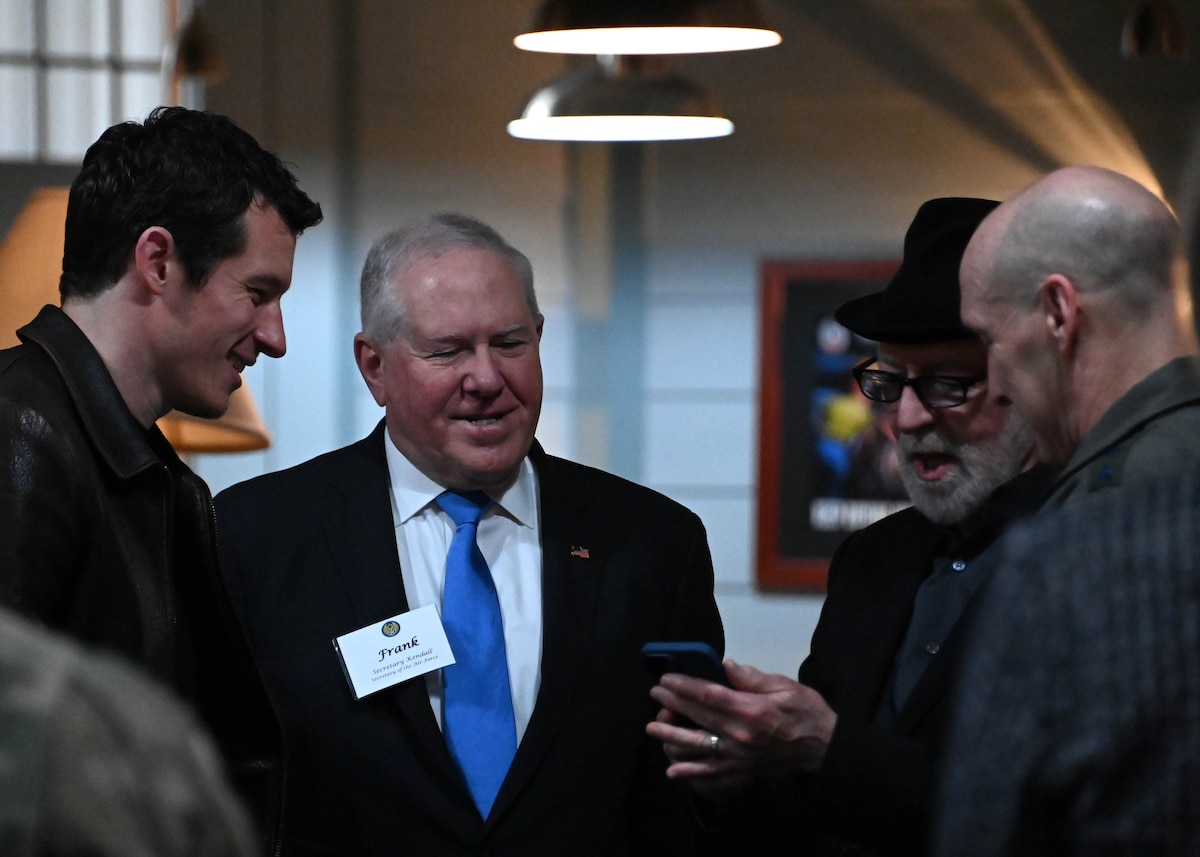 Four men stand in circle speaking to one another.