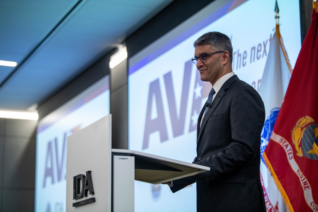 A man wearing business attire speaks behind a lectern.