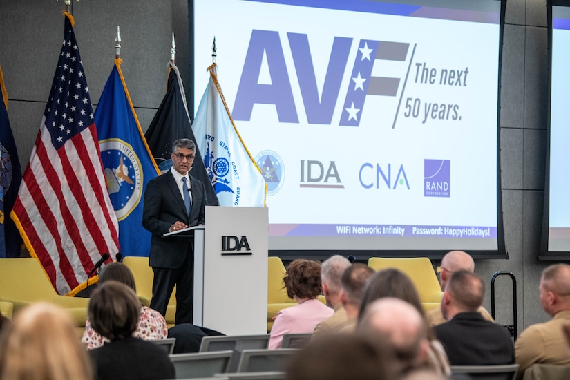 A man wearing business attire speaks from behind a lectern in front of a crowd of people