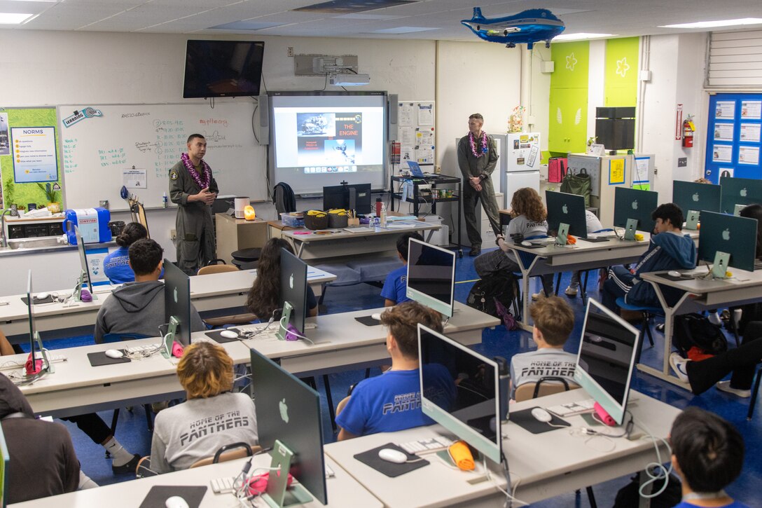 U.S. Marine Corps Cpl. Jacob Vasek and 1st Lt. Andrew Tilden with Marine Unmanned Aerial Vehicle Squadron (VMU) 3, Marine Aircraft Group 24, 1st Marine Aircraft Wing, educate students about the MQ-9A MUX/MALE at Aliamanu Middle School, Hawaii, Jan. 26, 2024. Students learned about MQ-9A capabilities and aviation career fields in the Marine Corps. (U.S. Marine Corps photo by Lance Cpl. Logan Beeney)