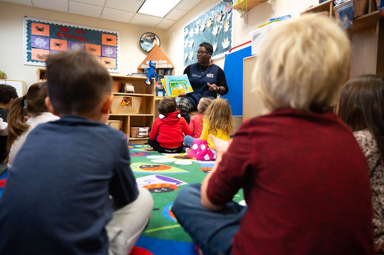 An adult reads a book to a group of children.