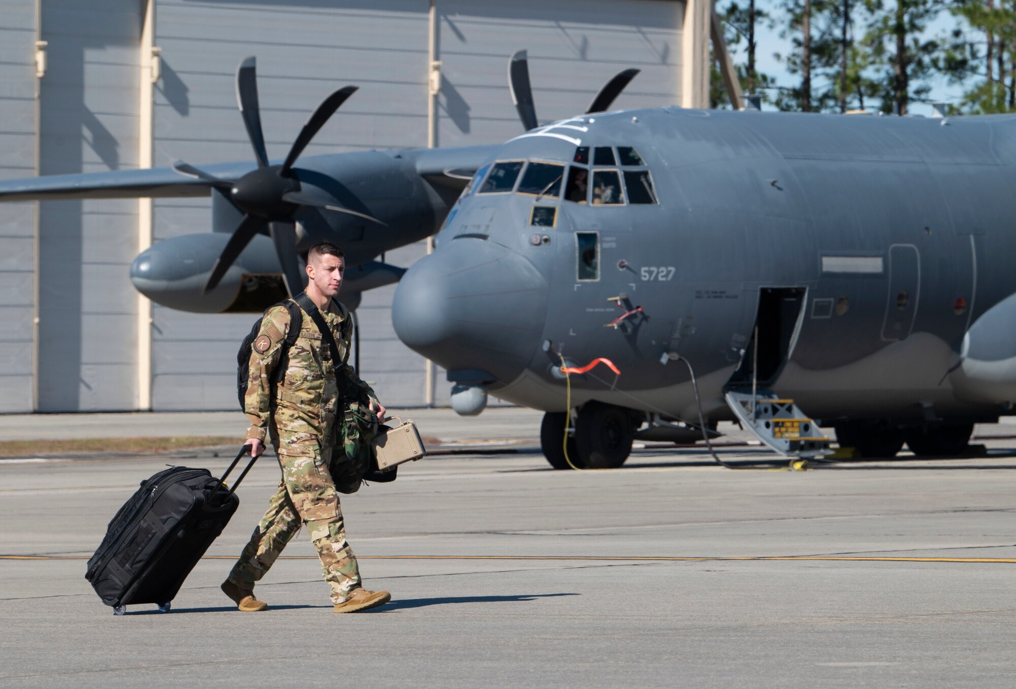 An Airman pulls a suitcase to an aircraft
