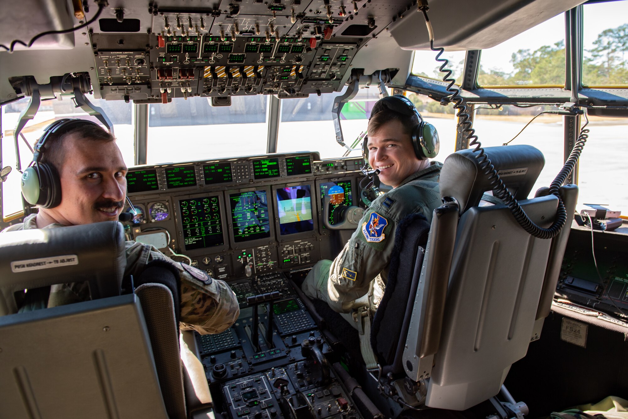 U.S. Air Force Capt. Jonathan Romanko (left), and Capt. Sebastian Wermuth, 71st Rescue Squadron pilots, smile inside the flight deck of an HC-130J Combat King II at Moody Air Force Base, Georgia, Jan. 10, 2024. The 71st RQS flew to Nellis AFB, Nevada, in support of exercise Red Flag which was established in 1975 for air forces of the U.S. and allied nations. (U.S. Air Force photo by Senior Airman Courtney Sebastianelli)