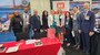 Groups of people from U.S. Army Corps of Engineers stand together to pose for a photo in business wear with booths surrounding them at the Small Business conference.
