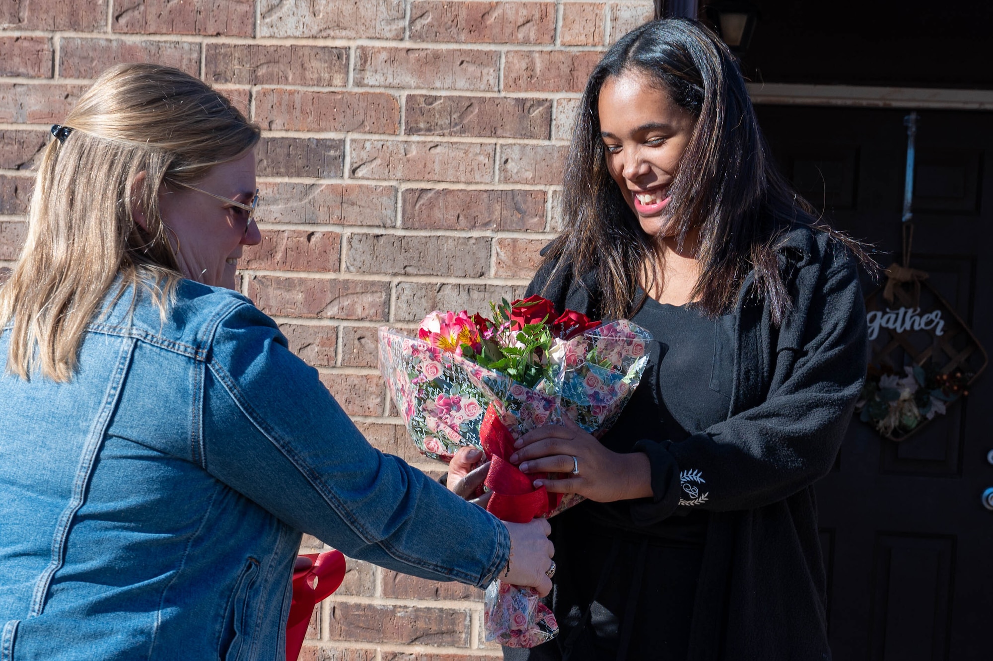 Daniele Fabis (left), 97th Force Support Squadron Family Child Care (FCC) coordinator, gives Roisveli Matos, FCC provider, a bouquet of flowers at a ribbon-cutting ceremony at Altus Air Force Base, Oklahoma, Jan. 29, 2024. The ceremony was held to celebrate Matos opening her FCC home on base to support Airmen. (U.S. Air Force photo by Airman 1st Class Heidi Bucins)