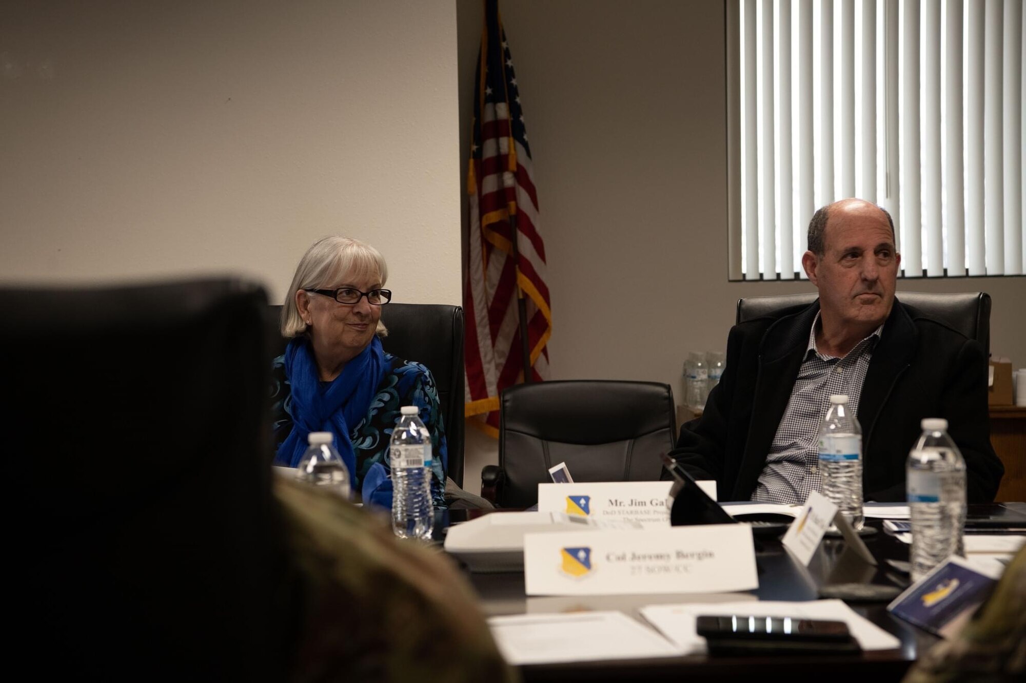 A man and women sit at a conference table during a meeting.