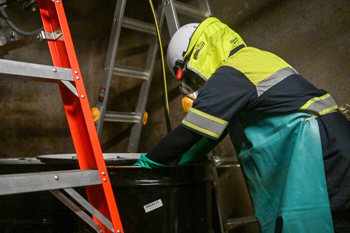 A member in support of Joint Task Force-Red Hill (JTF-RH) guides a line into a fuel drum to remove residual fuel from the Red Hill Bulk Fuel Storage Facility (RHBFSF) Jan. 22, 2024, Halawa, Hawaii.